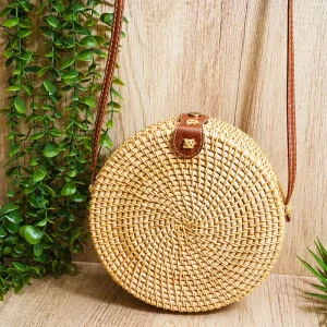 round rattan crossbody bag displayed in a natural interior