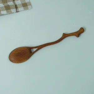 Full view of the curved branch-inspired handle of a wooden Y spoon