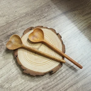 Two heart-shaped wooden spoons arranged on a wood slice