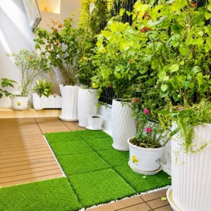 Grass floor tiles arranged beside potted plants and wood decking