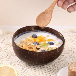 Coconut bowl filled with cereal and fruit while a hand holds a wooden spoon