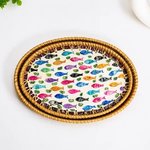 Nested rattan fish motif trays in a tabletop setting with a plant and plate