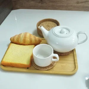 Round woven coasters beneath a cup and teapot on a breakfast tray