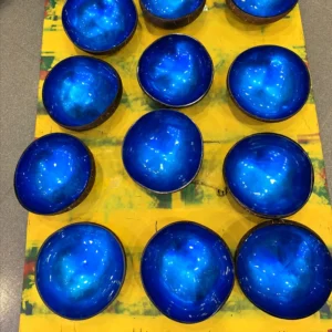 A group of blue lacquer coconut bowls, showing natural variation in shape and reflections.