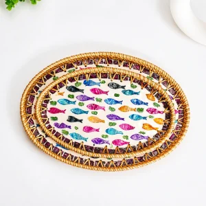 Oval rainbow fish trays arranged on a tabletop beside a plant and white plate