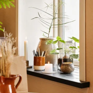 Coconut shell tealight candle holder displayed beside plants and candles on a tiled windowsill