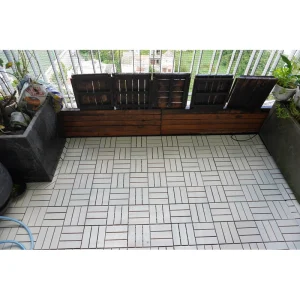 White twelve-slat wood tiles installed across a planted balcony floor