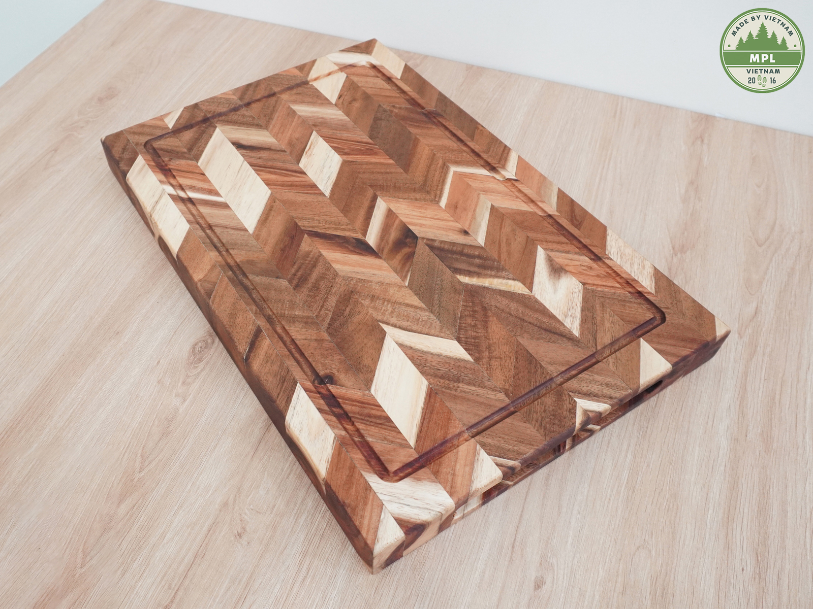 Herringbone wooden cutting board with a juice groove on a wooden tabletop