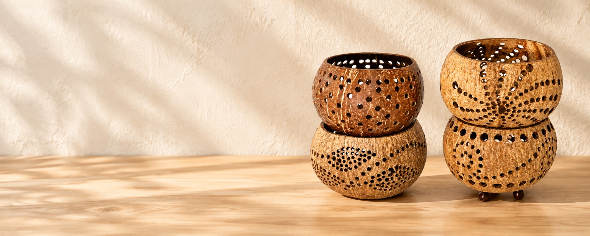 Four perforated coconut shell candle holders on a warm wooden tabletop