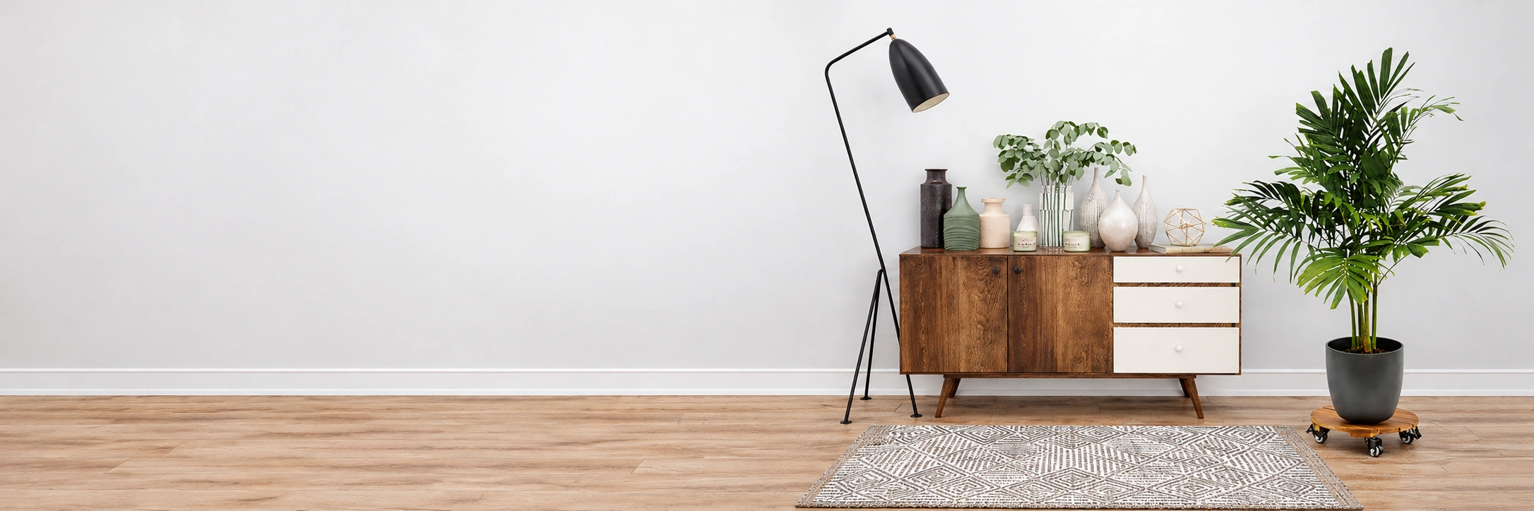 Round wooden plant caddy with swivel wheels supporting a palm in a bright living room